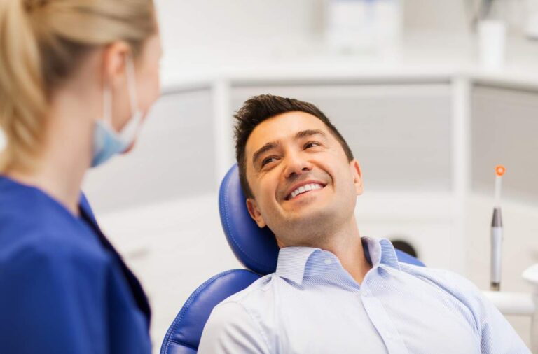 A relaxed adult patient wearing a dental bib while a clinician places a small sedation mask over the nose.