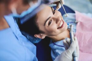 Adult patient uses a hand signal while speaking with a dentist in a calm examination room.