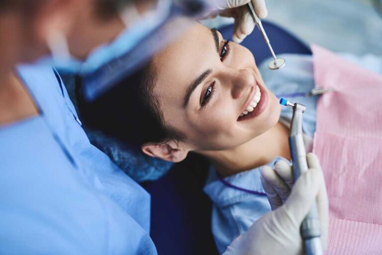Adult patient uses a hand signal while speaking with a dentist in a calm examination room.